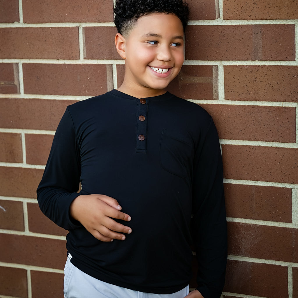 Young boy wearing a black long-sleeve shirt against a brick wall