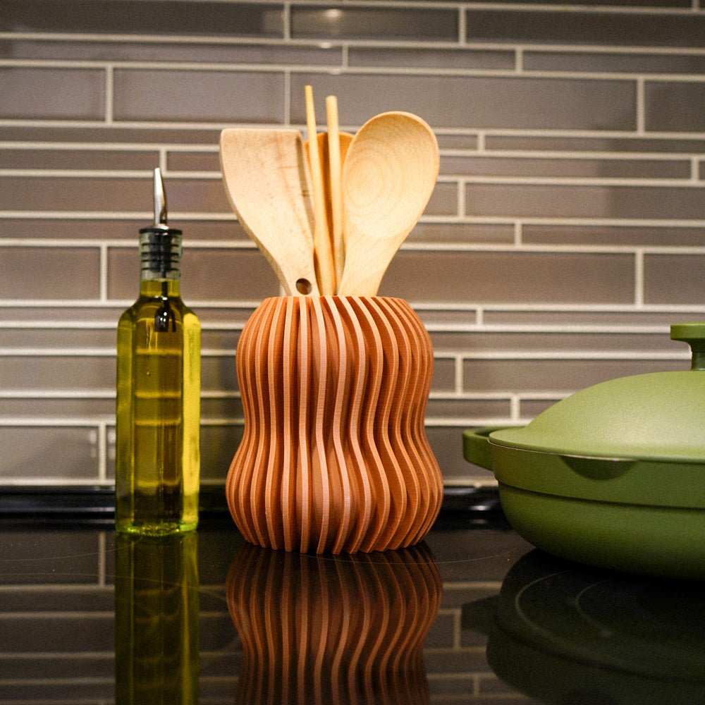 Wooden utensil holder with spoons next to a bottle of oil on a kitchen counter.