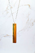 Necklace with a wooden pendant with vertical stone inlay on a marble background