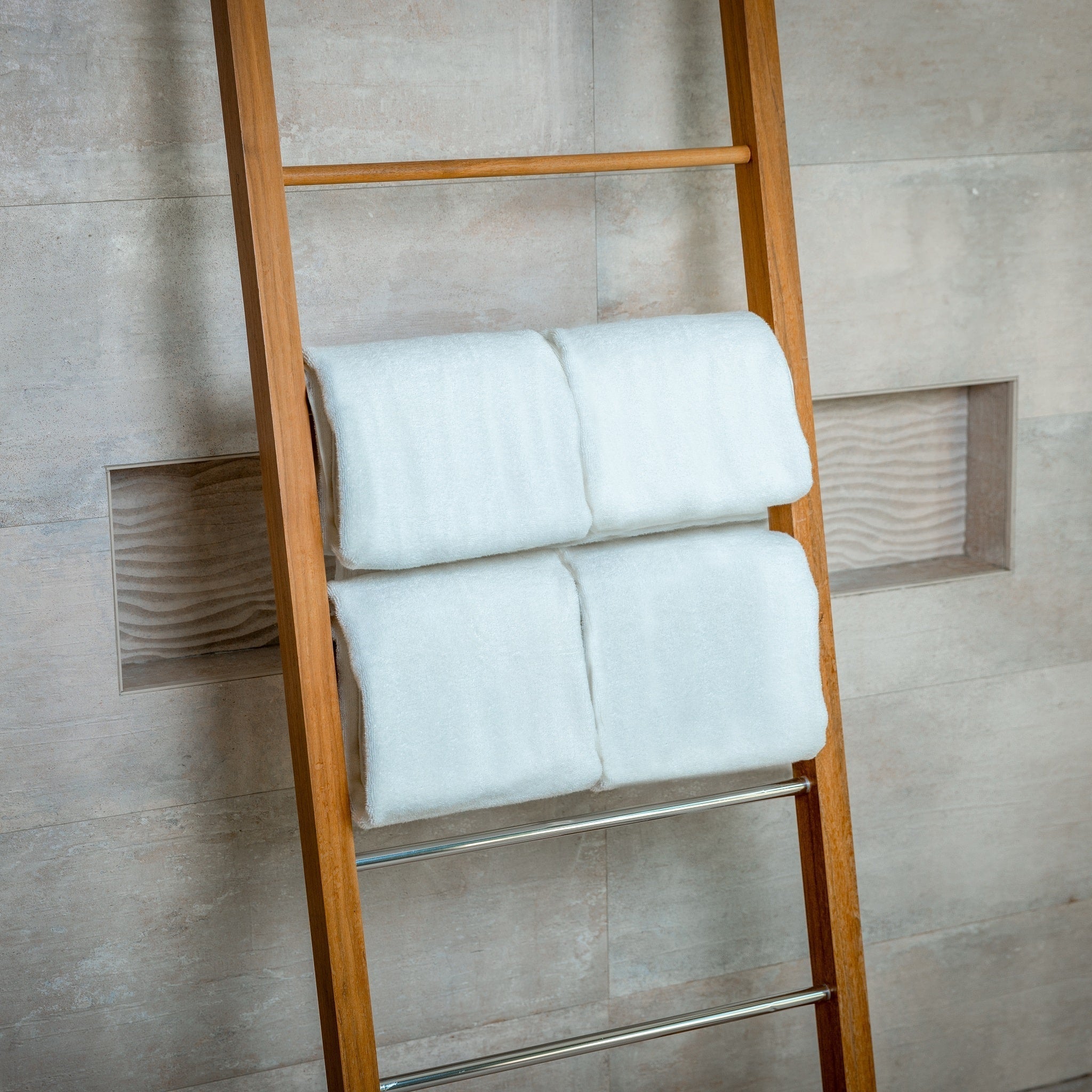 Wooden towel ladder with white towels against a tiled wall.