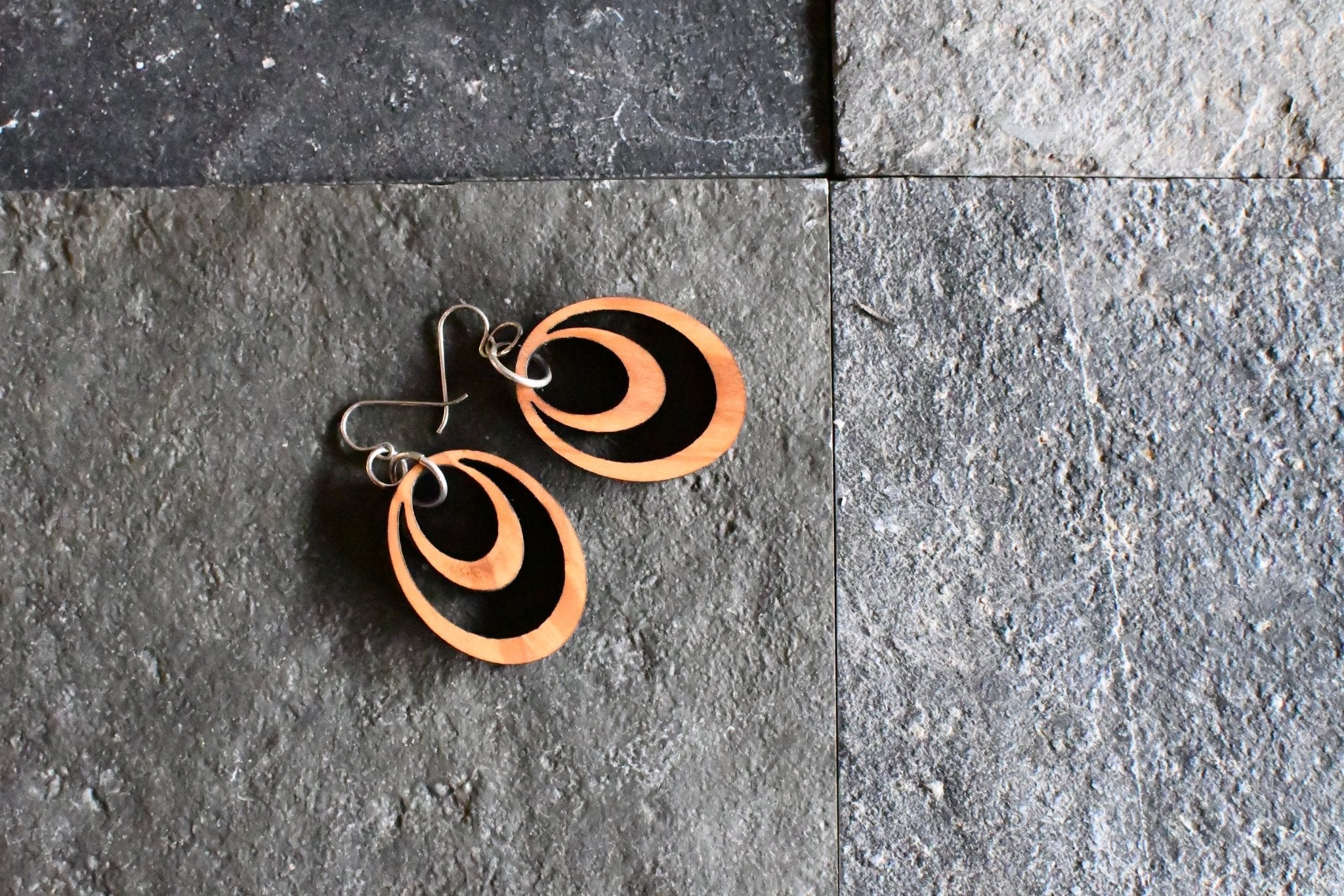 Pair of earrings with circular design on a gray stone surface