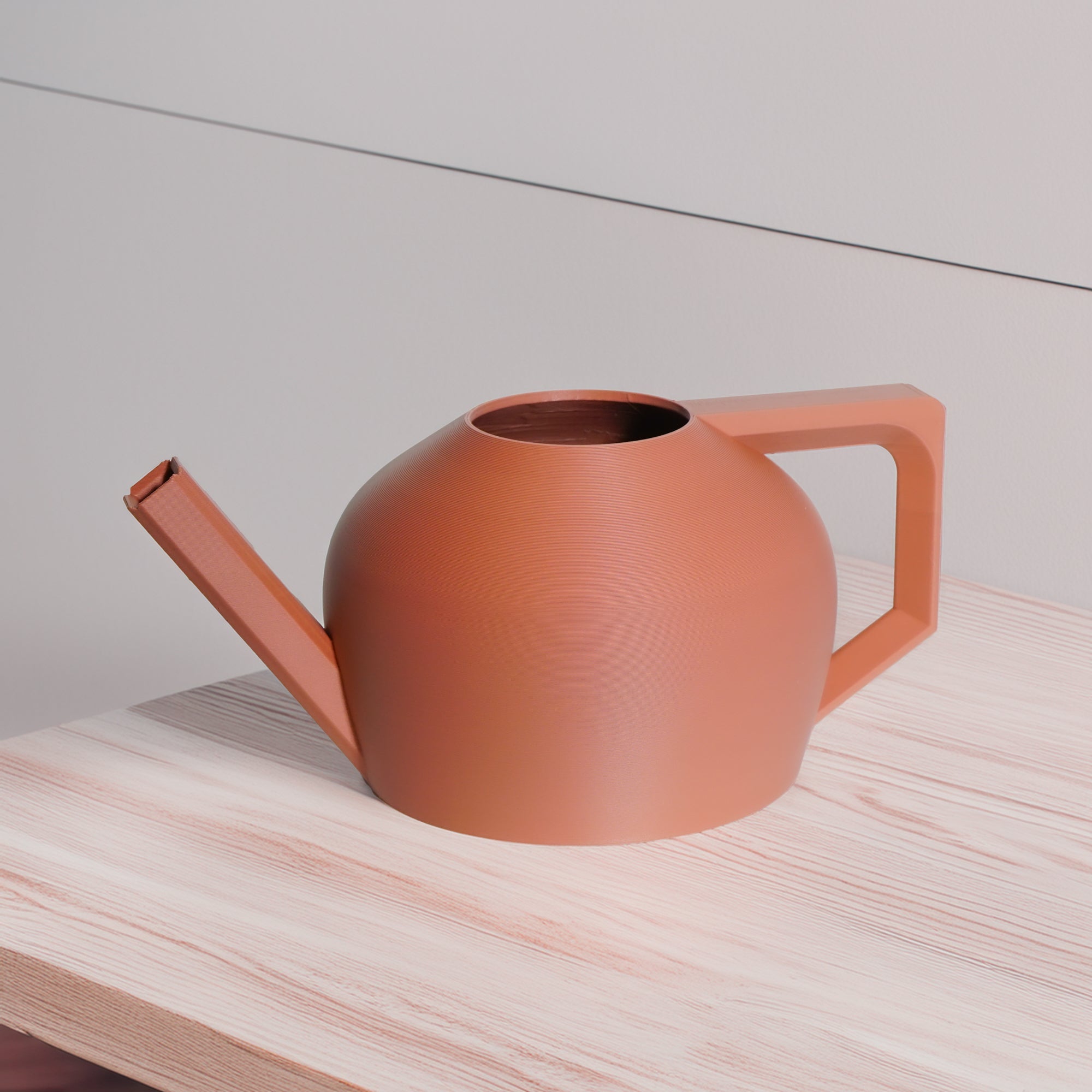 Terracotta-colored watering can on a light wooden surface with a neutral background