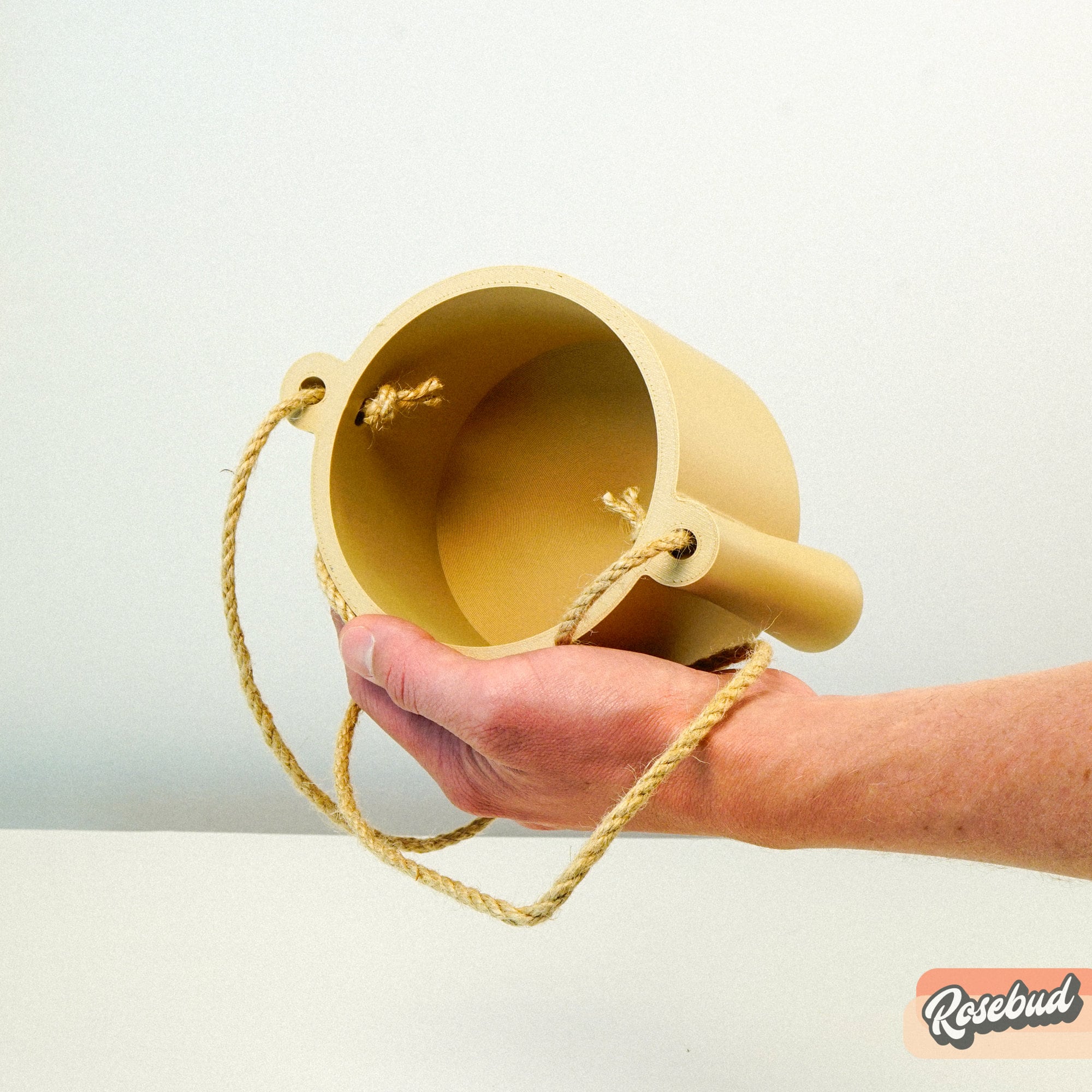 Hand holding a 3D printed Elysian hanging planter, on a light gray background