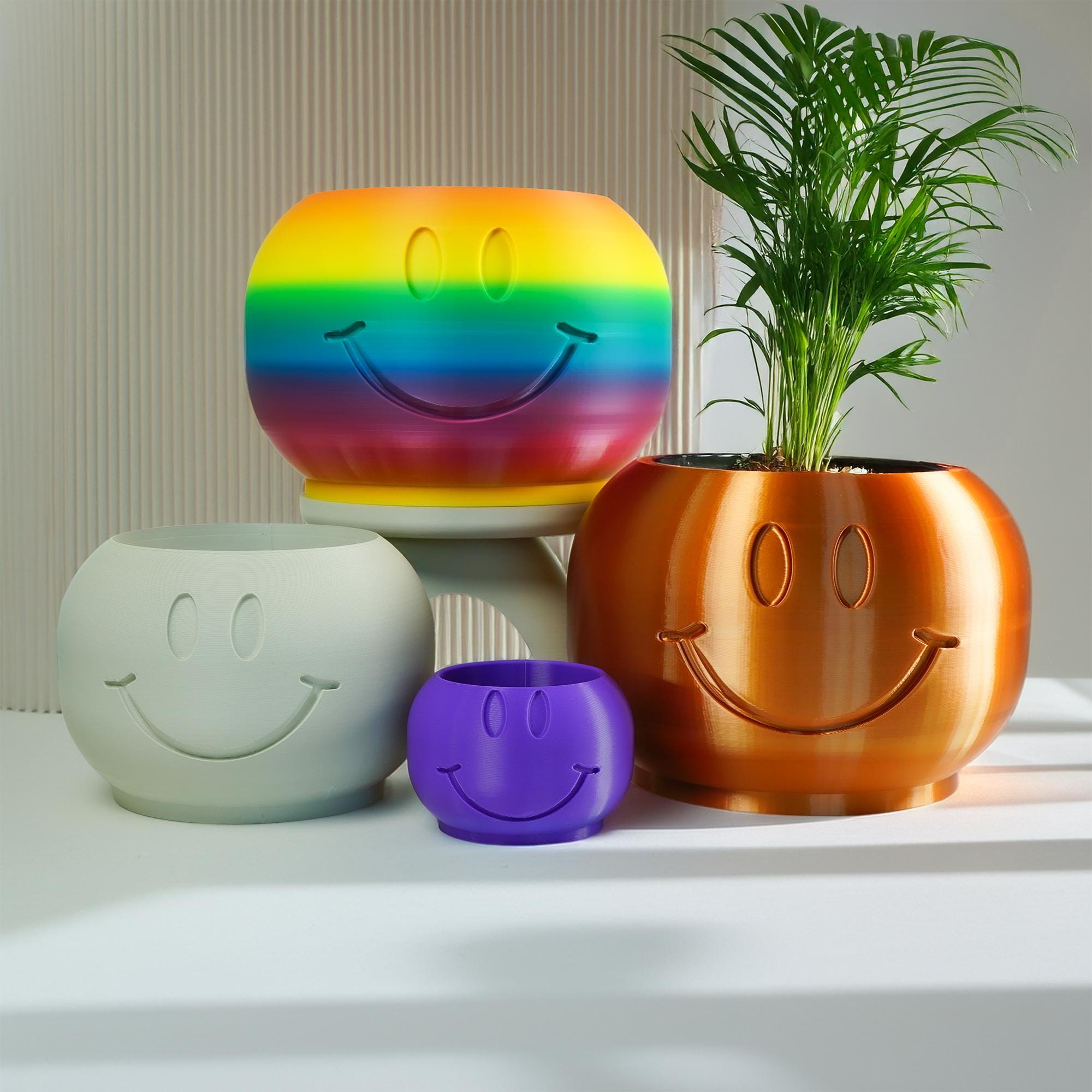 Set of colorful smiley face planters on a neutral background
