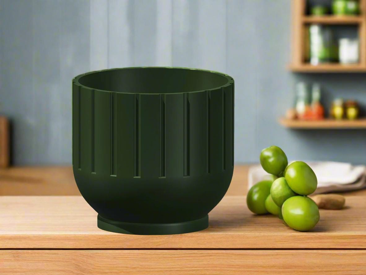 Green ceramic bowl on a wooden surface with green fruits in the background