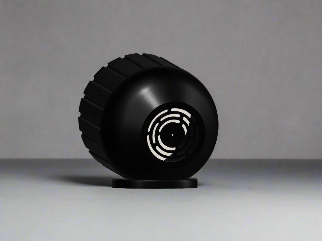 Black spherical planter on it's side to show drainage system on a gray background