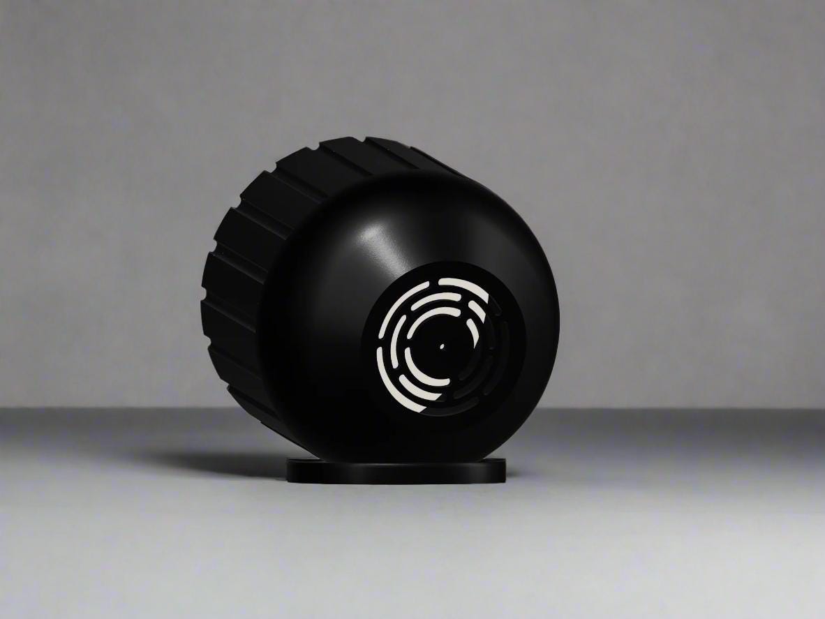 Black spherical planter on it's side to show drainage system on a gray background