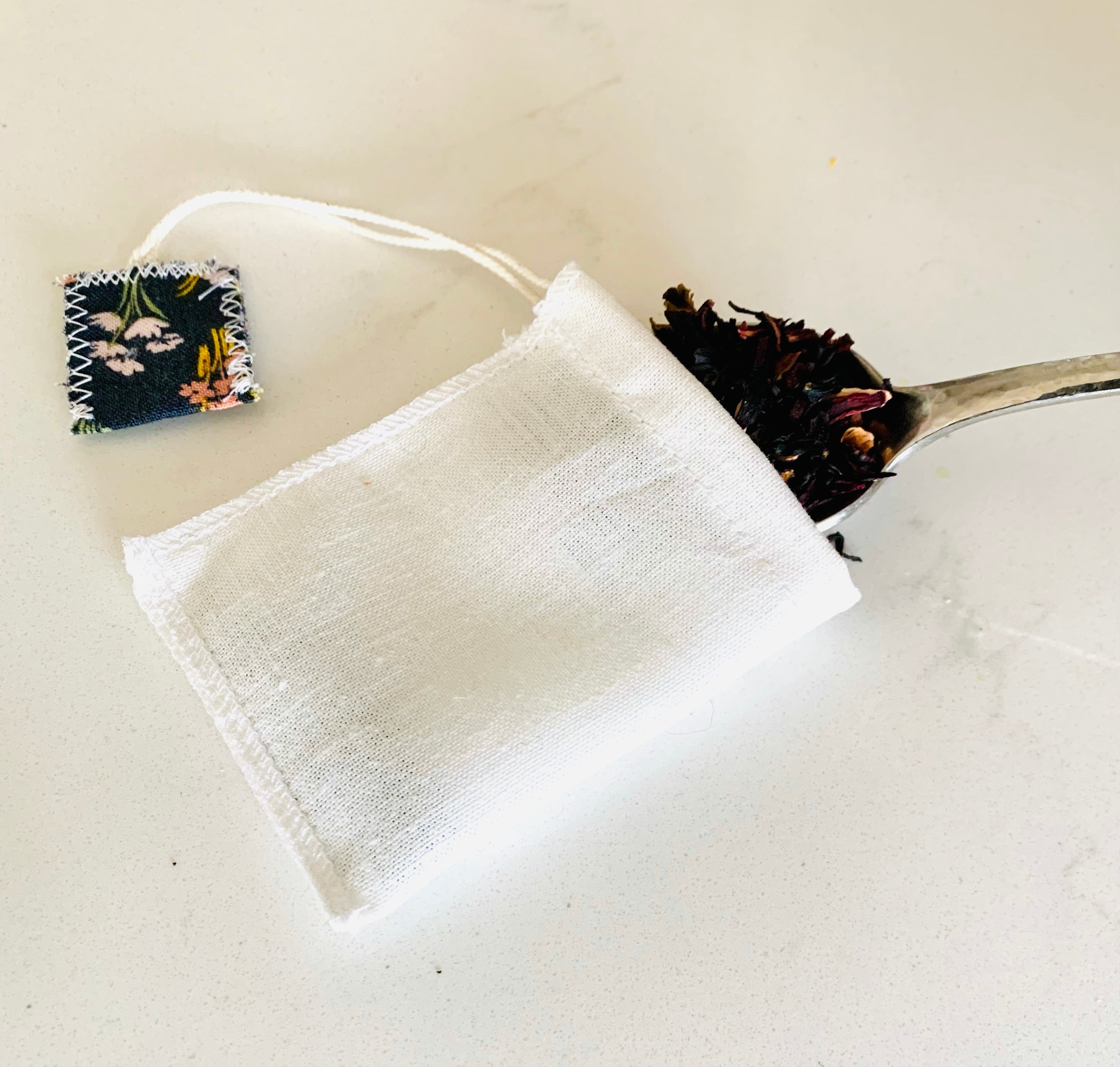 White tea bag with dried herbs on a white background
