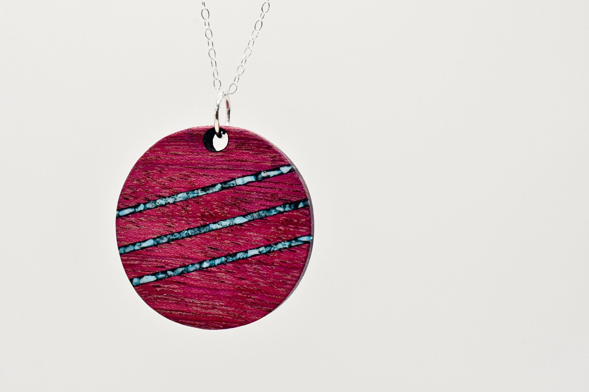Wooden pendant necklace blue inlay on a light gray background