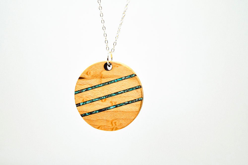Wooden pendant necklace with blue accents on a white background