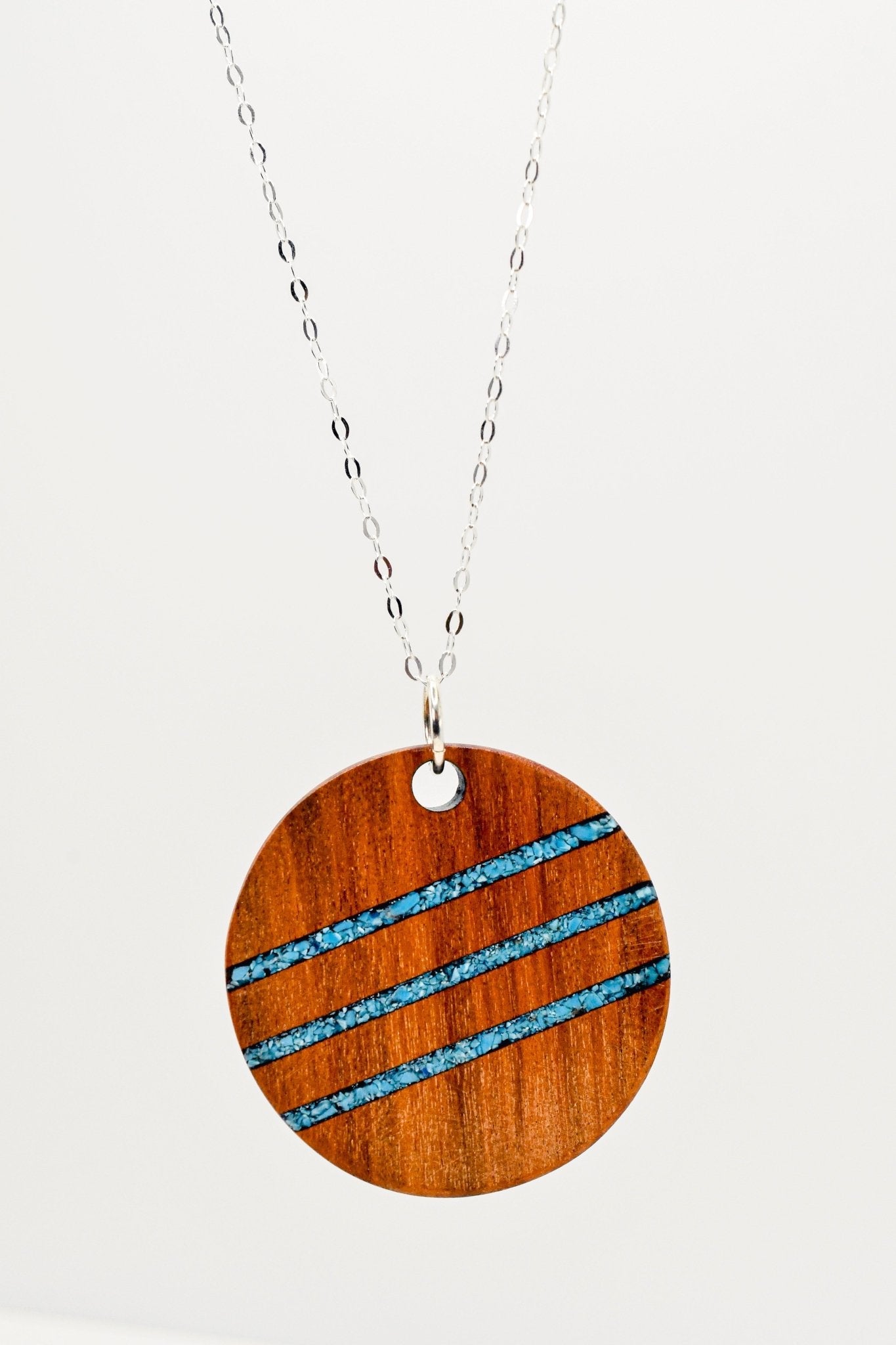 Wooden pendant necklace with blue accents on a white background