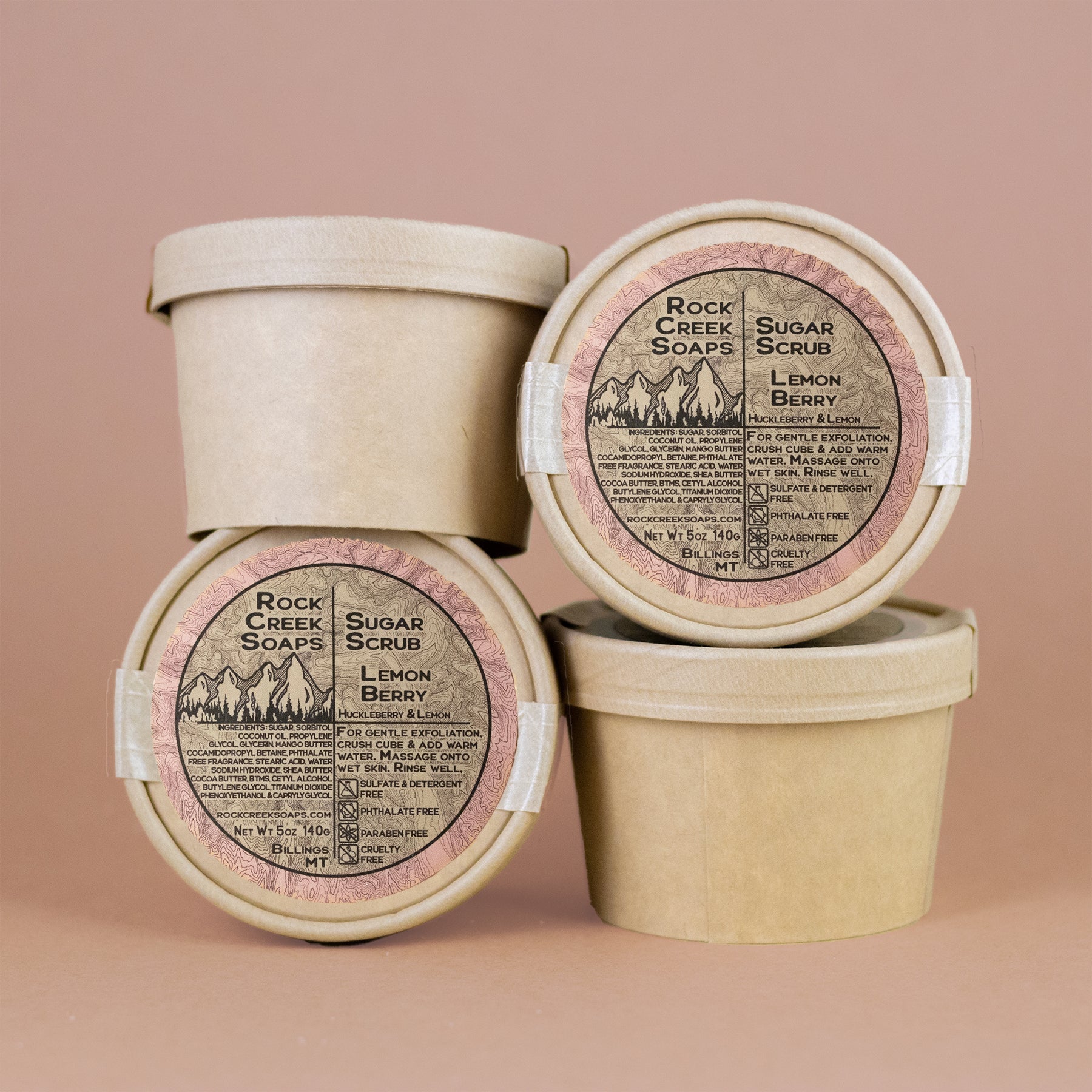 Three containers of Rock Creek Soaps Lemon Berry Sugar Scrub on a beige background