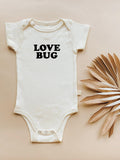 White baby onesie with 'LOVE BUG' text on a beige background