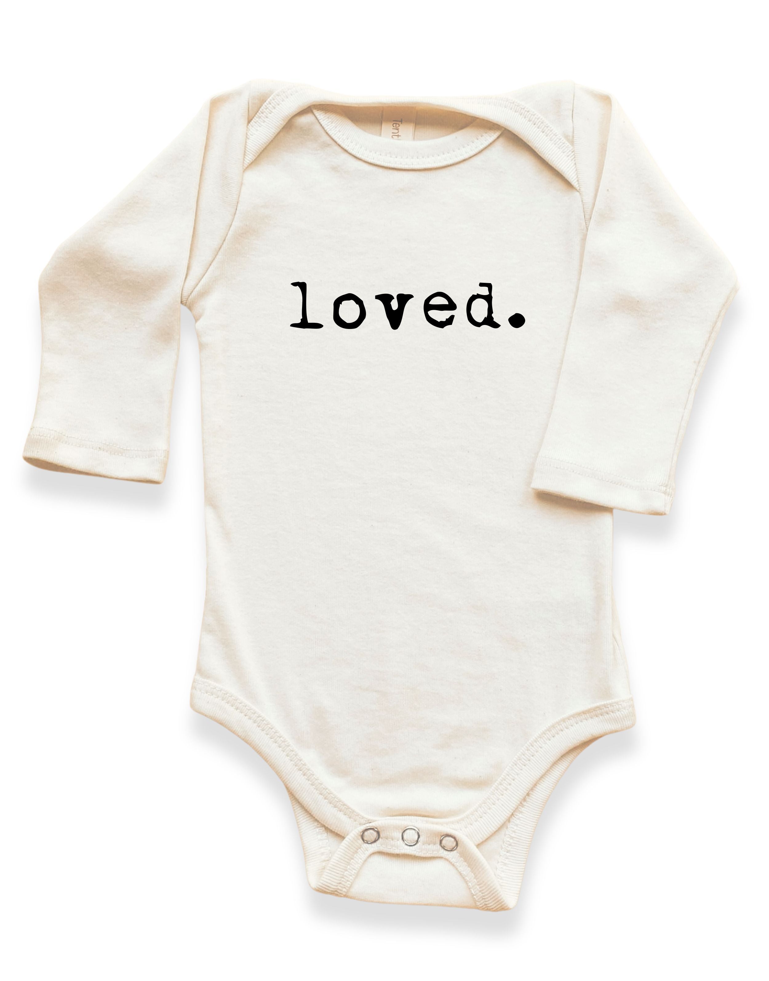 White baby onesie with 'loved.' text on a white background