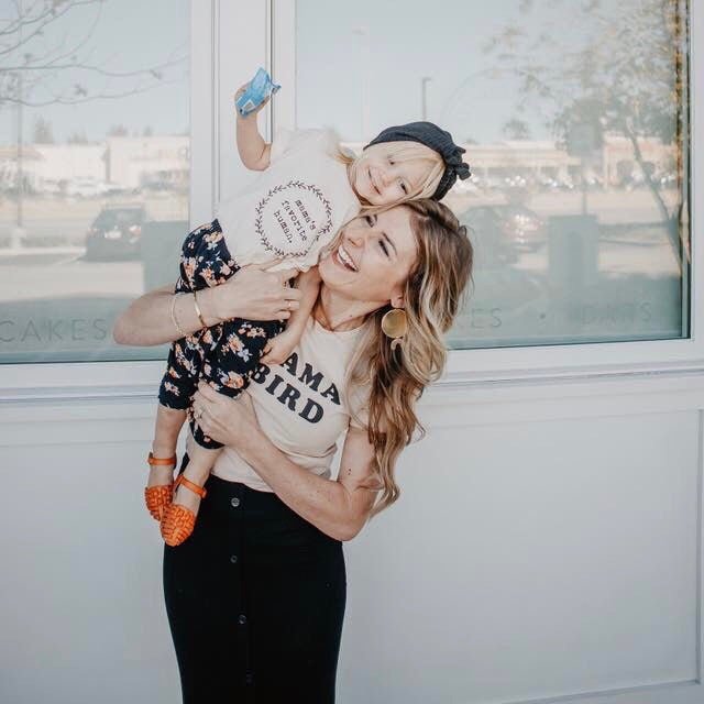Woman holding a child in front of a window with a blurred outdoor view