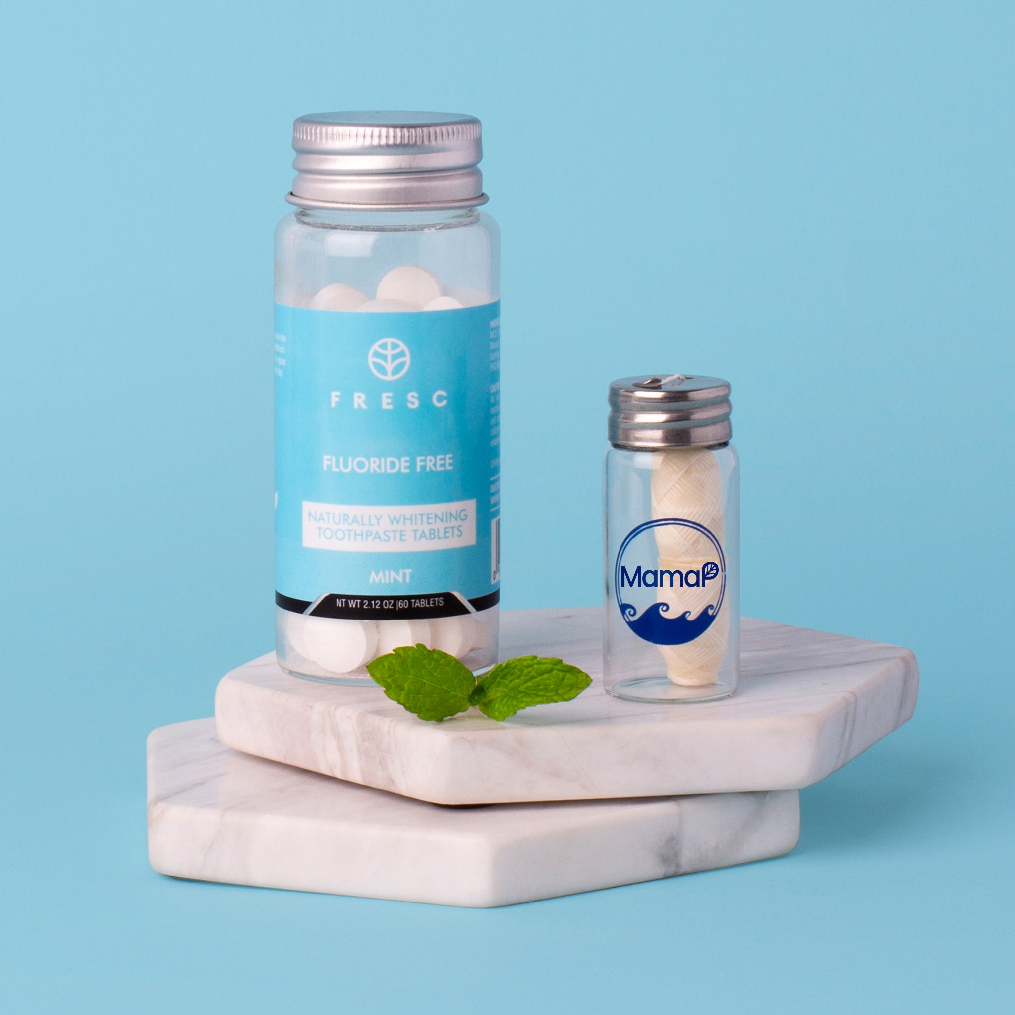 Two bottles with dental products on a marble stand with a blue background