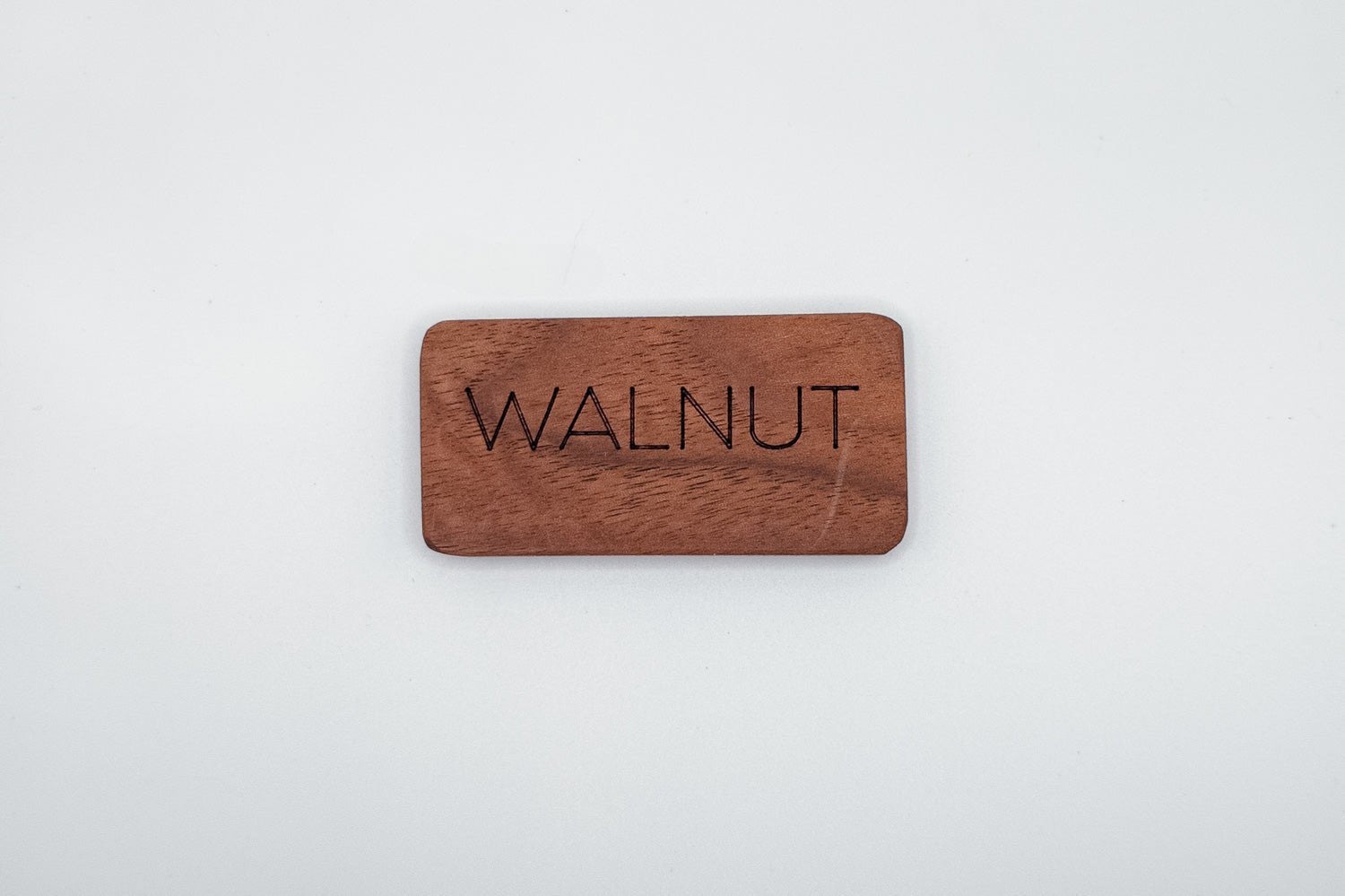 Wooden money clip with 'WALNUT' engraving on a white background