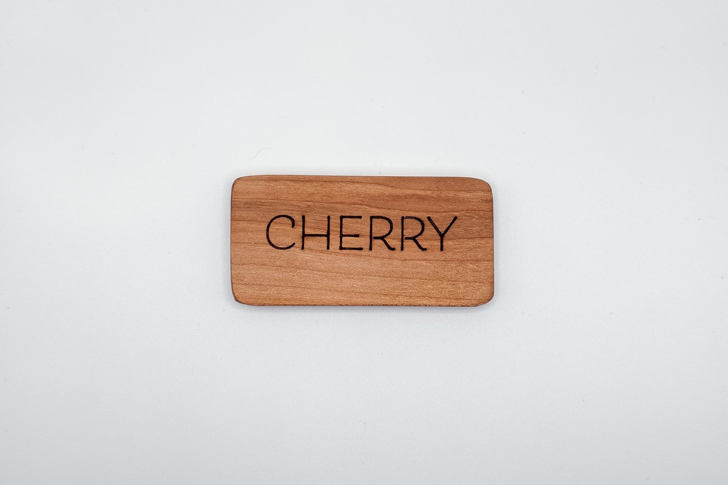 Wooden money clip with 'CHERRY' engraved on a light gray background