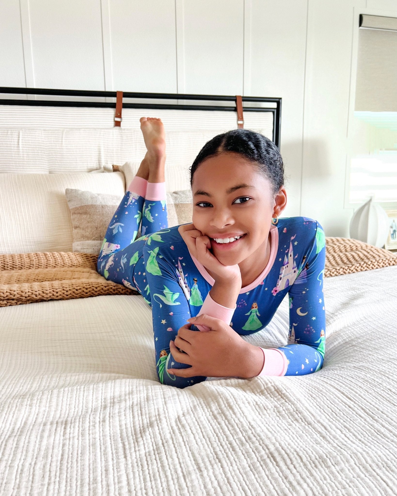 Child wearing blue pajamas with green frog pattern on a bed