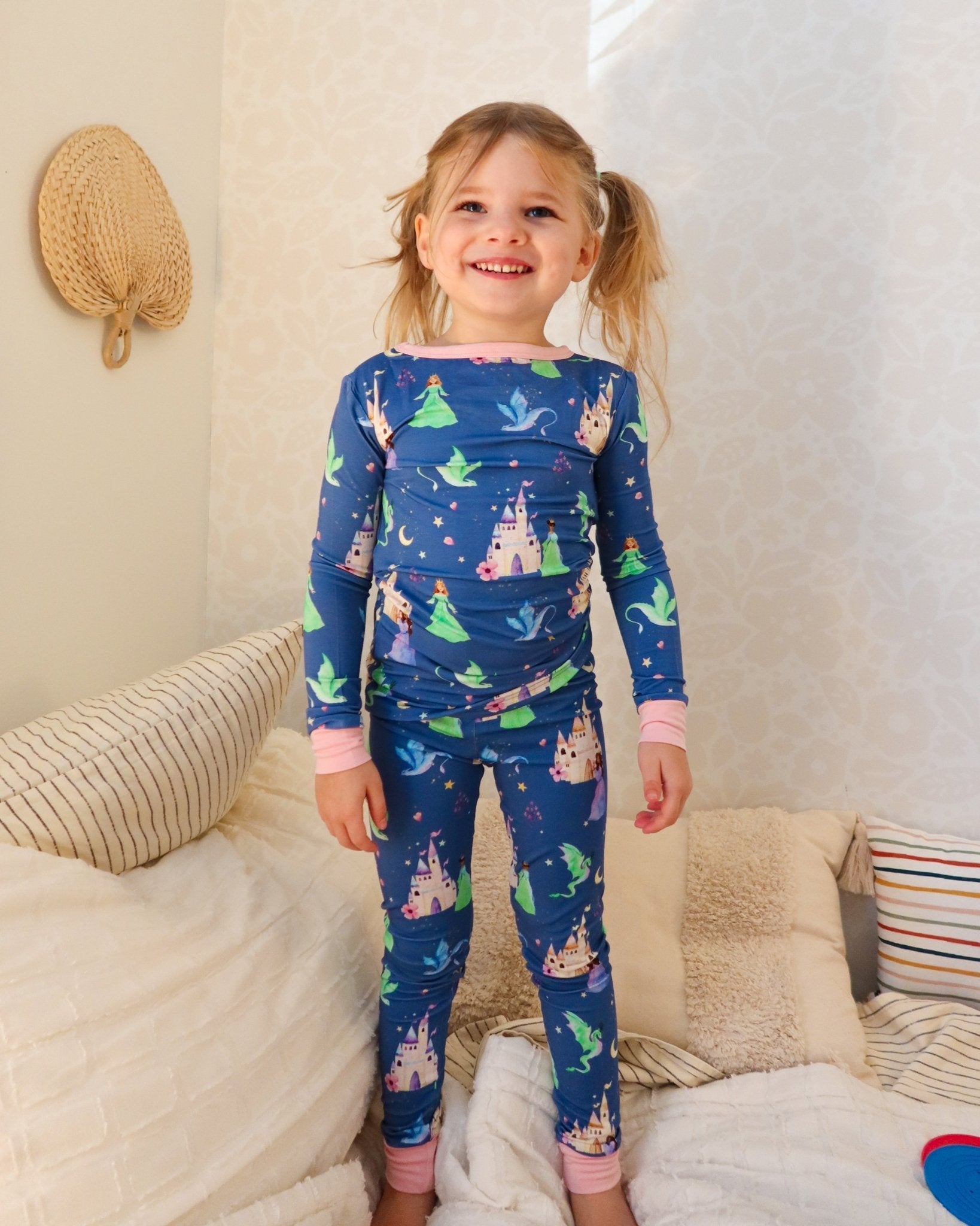 Child wearing blue pajamas with fairy tale design in a cozy room.