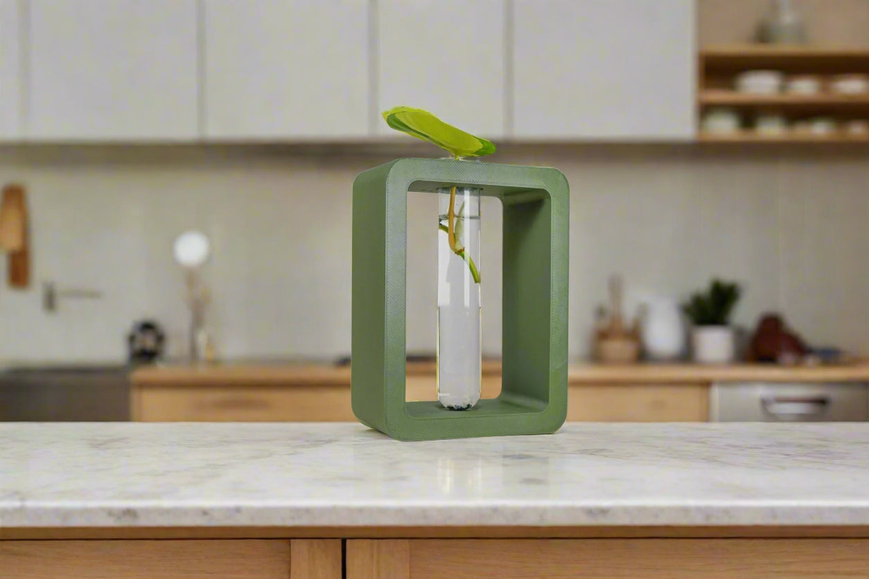 Green cube shaped vase on a marble countertop with a blurred kitchen background