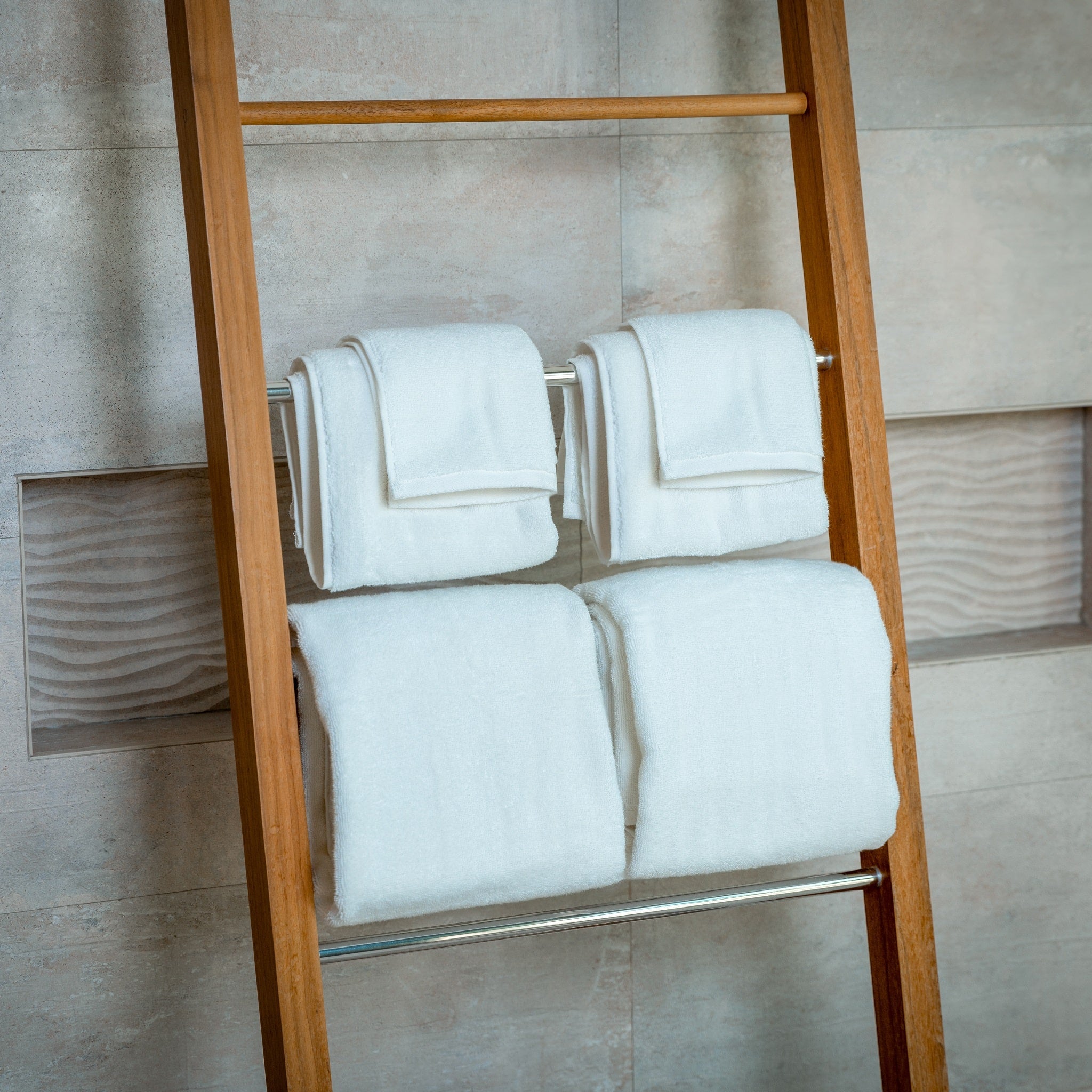 Towel rack with white towels against a tiled bathroom wall