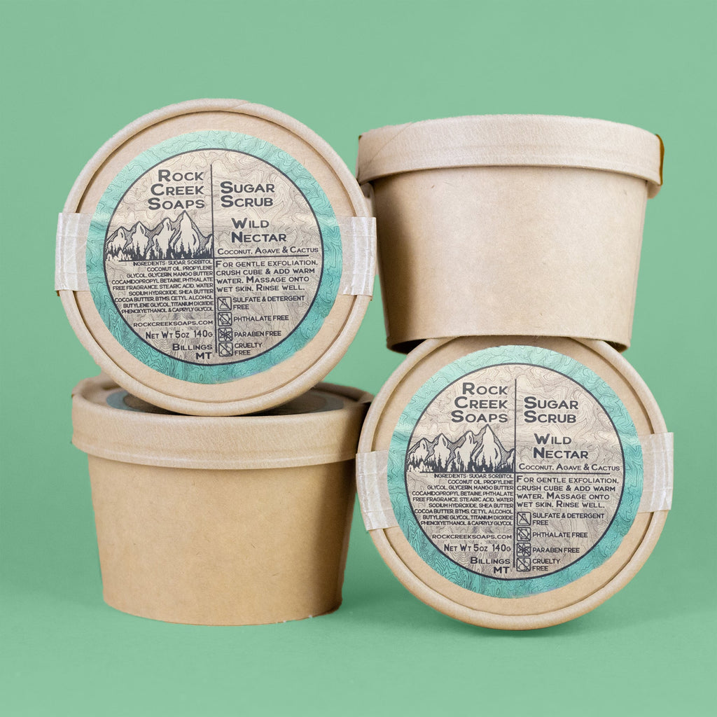 Three containers of Rock Creek Soaps Sugar Scrub on a green background