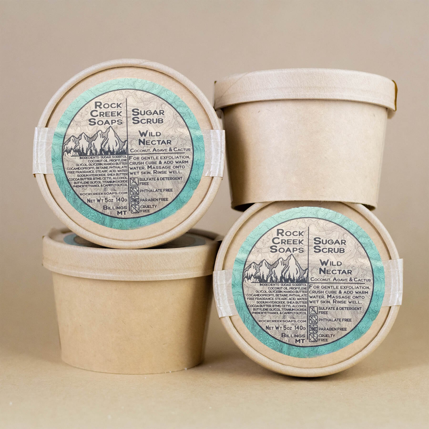 Three containers of Rock Creek Soaps Sugar Scrub on a beige background