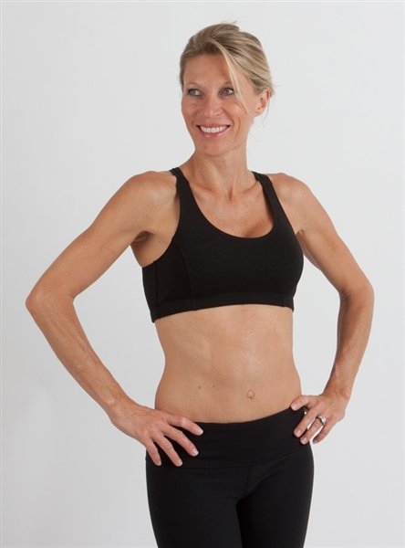 Woman wearing a black sports bra and leggings on a plain background
